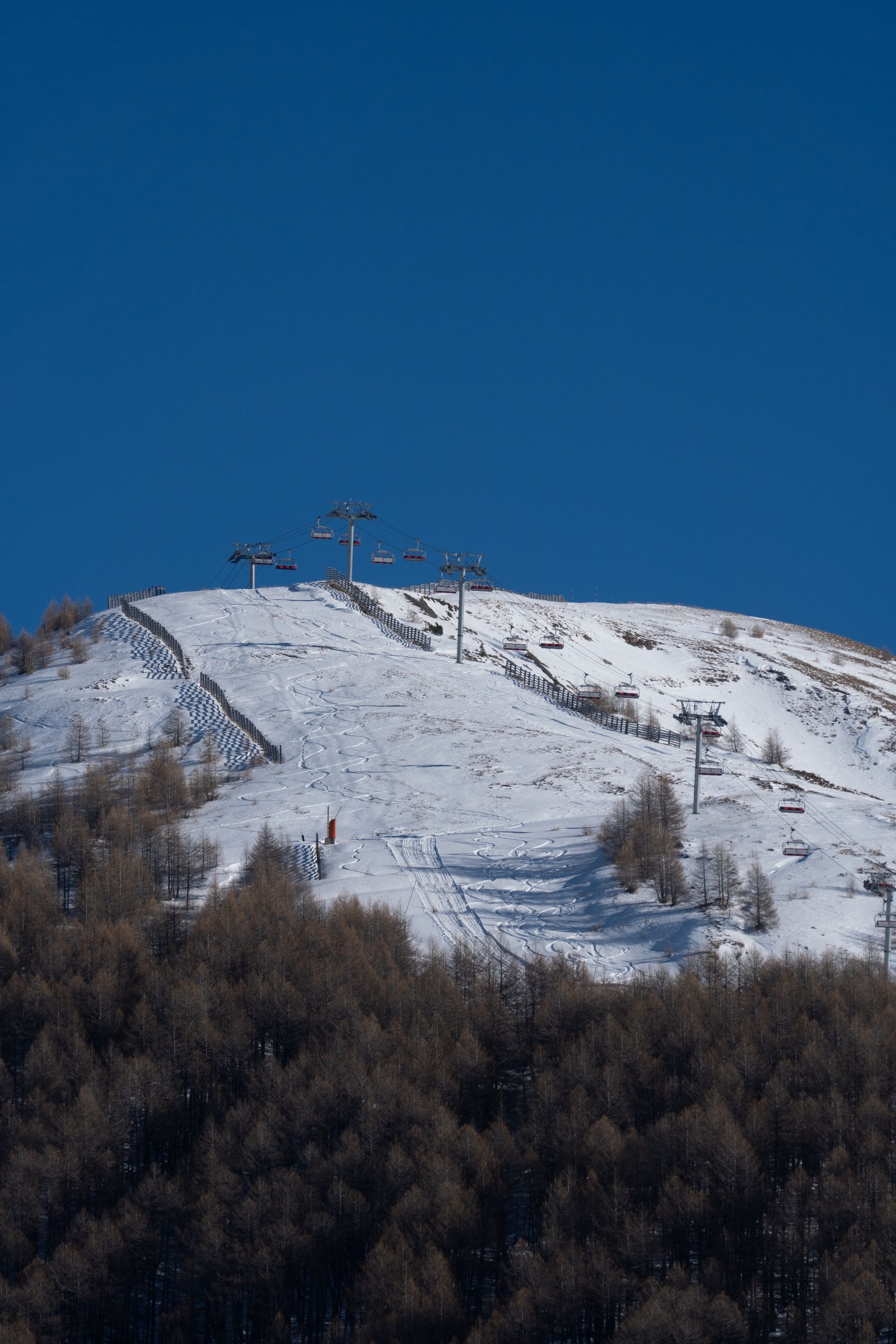Chairlift line climbing a snow-covered ski slope under a deep blue sky