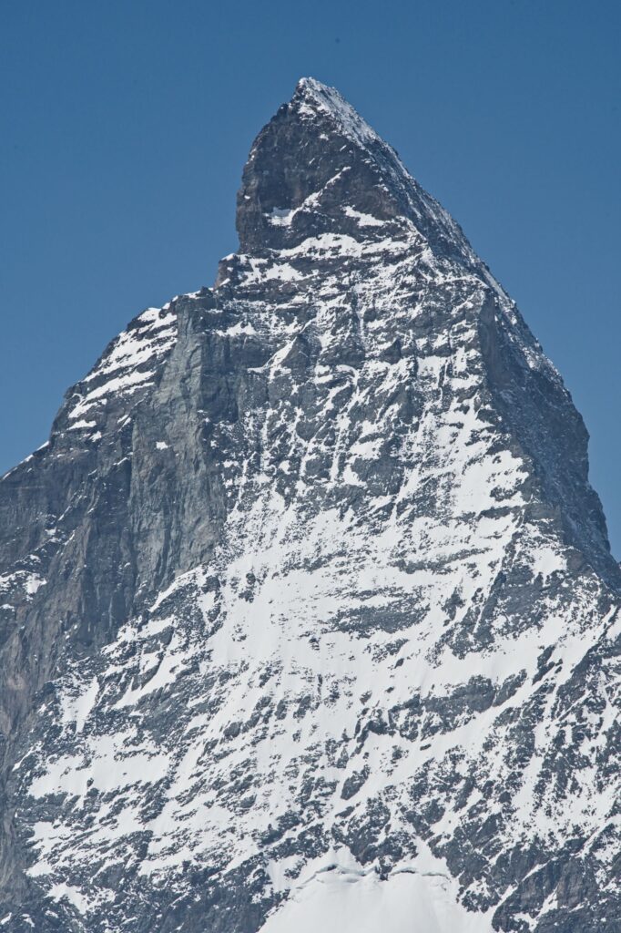 Close view of the snow-streaked pyramid of the Matterhorn against a blue sky