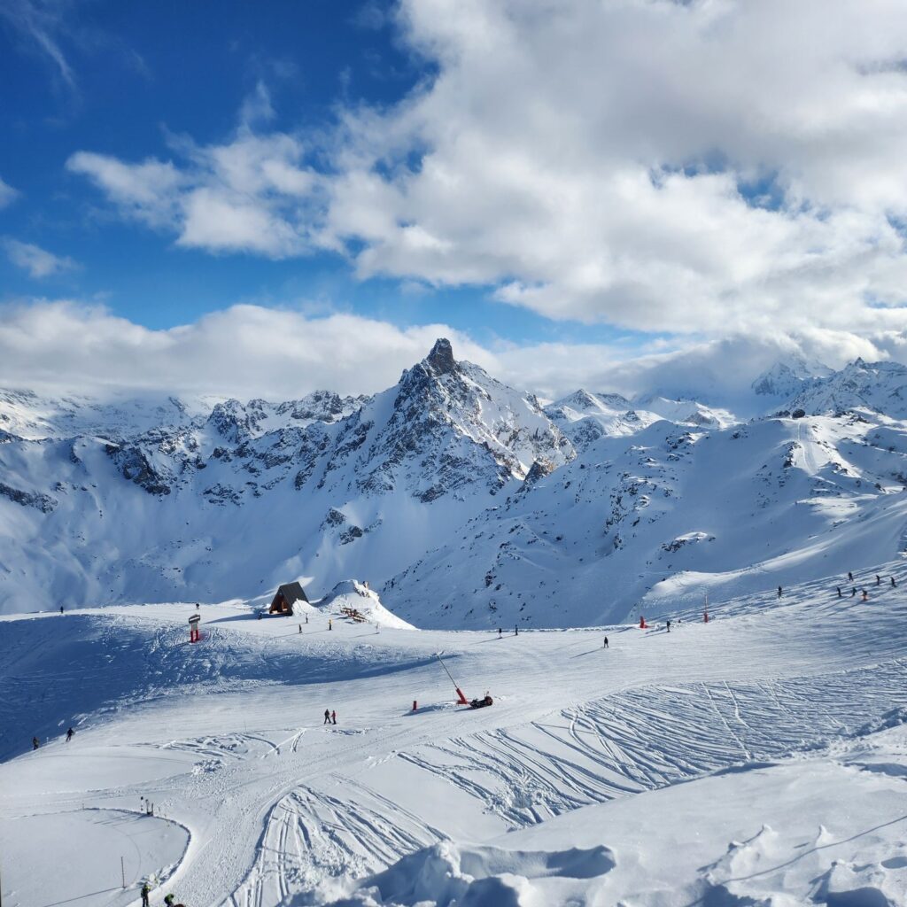 Wide snowy ski slopes beneath jagged Alpine peaks in the French Alps