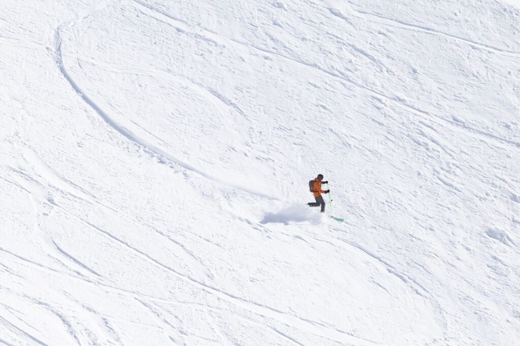 A lone skier carving tracks down a wide, untouched snowy slope